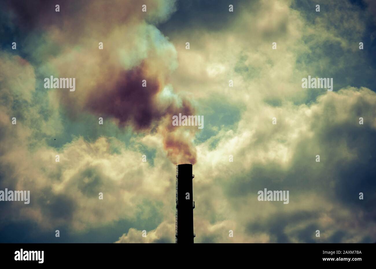 technogenic contrasting background tip of the black silhouette pipe with smoke sky with bright clouds and sun backlight Stock Photo