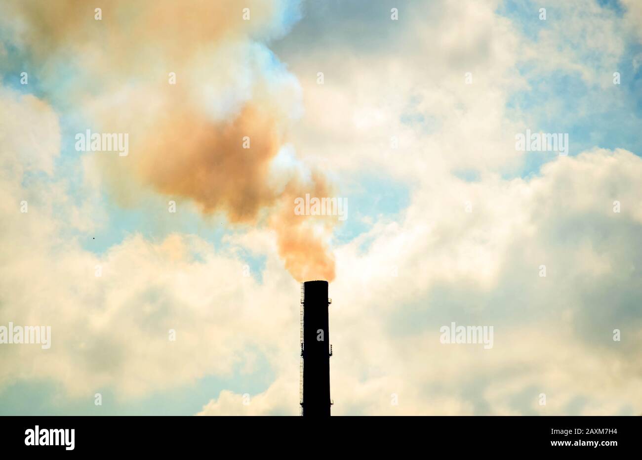 technogenic contrasting background tip of the pipe with smoke sky with clouds Stock Photo