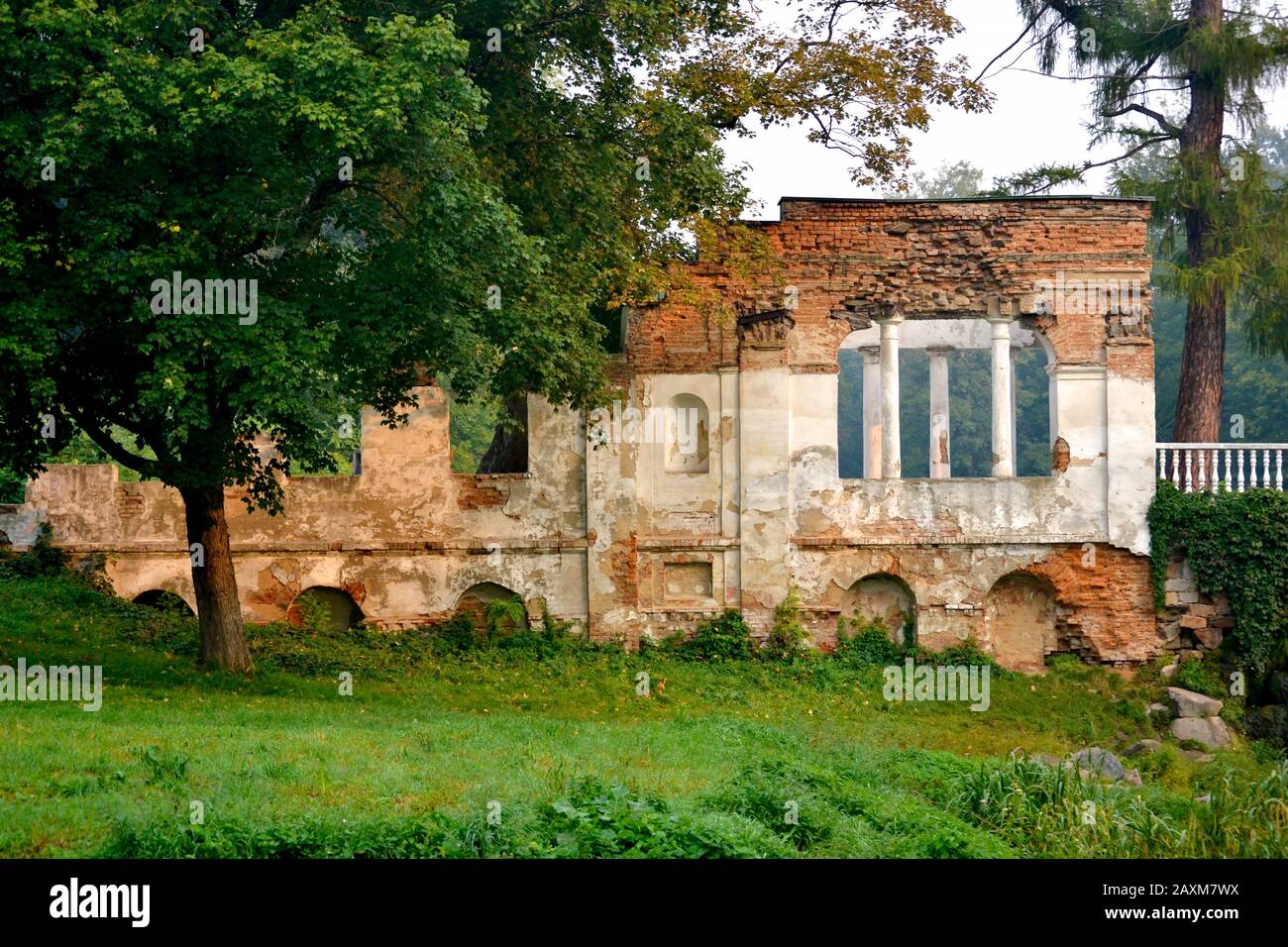 Ruins of red brick with white railing with columns and tree in the park Stock Photo