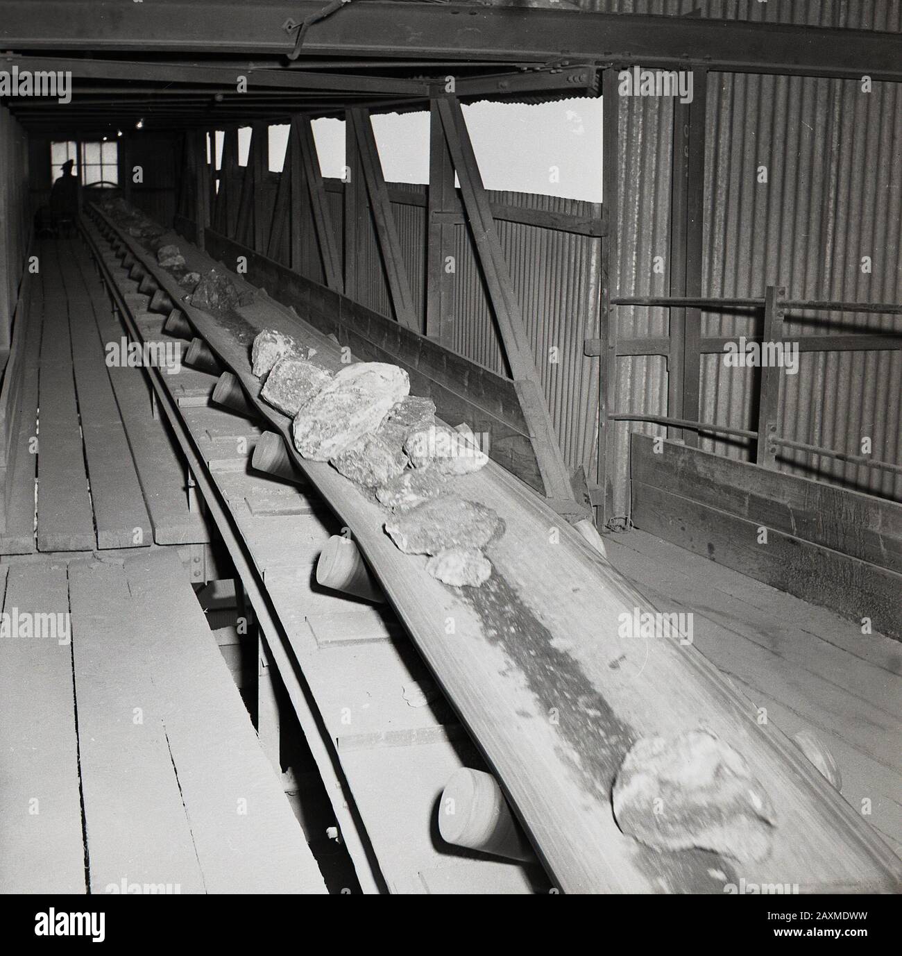 1960s, historical, covered conveyor belt in an open pit or mine carrying mined naturals minerals, rocks, which contain low concentrations of uranium ore, South Africa. Stock Photo