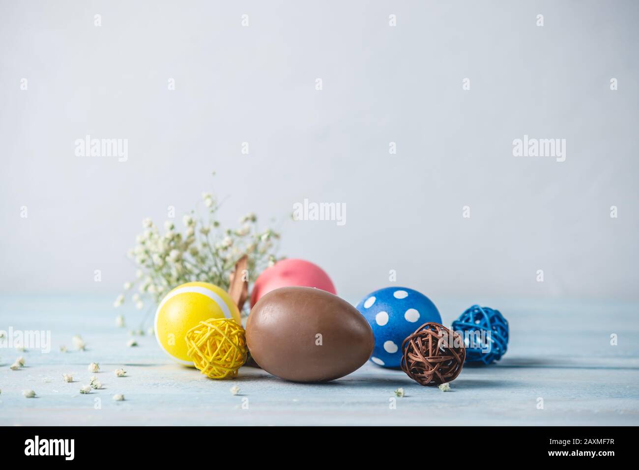 Bright colorful Easter eggs with spring flowers on a blue background. Festive spring Easter card. Stock Photo