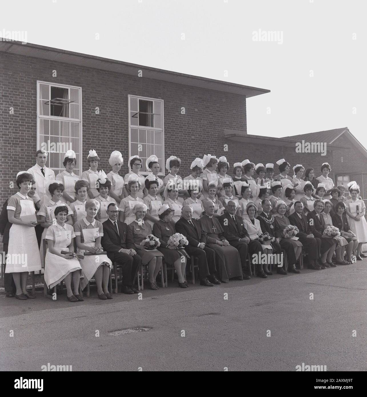 1965, historical, group photo of newly qualified nurses in their uniforms, senior nursing staff, priest and other local dignitaries, outside Stoke Mandeville Hospital, Bucks, England, UK. The origins of the hospital, which in 1944 saw the establishment of the National Spinal Injuries Centre there, came from the cholera epidemic that swept England in the 1830s. Stock Photo