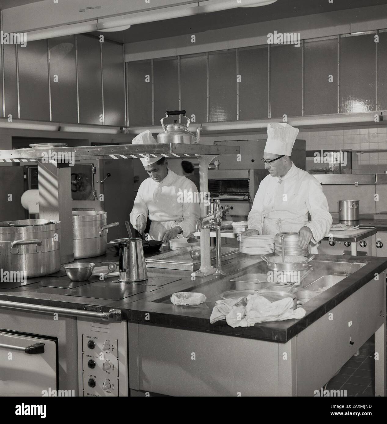 1960s, historical, two male Chefs wearing traditional uniforms or Chef's white jackest and tall hats - working in a large kitchen, England, UK. Stock Photo