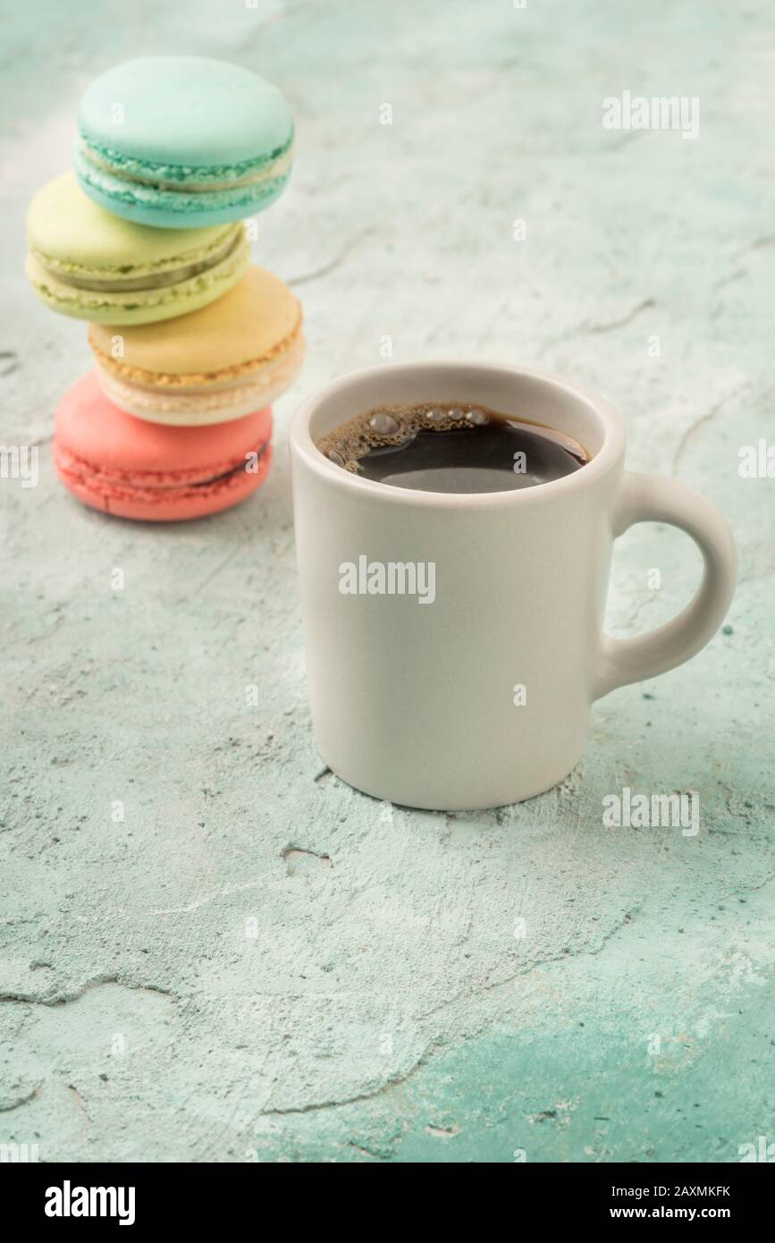 pile of colorful french macaroons and a cup of coffee on table Stock Photo