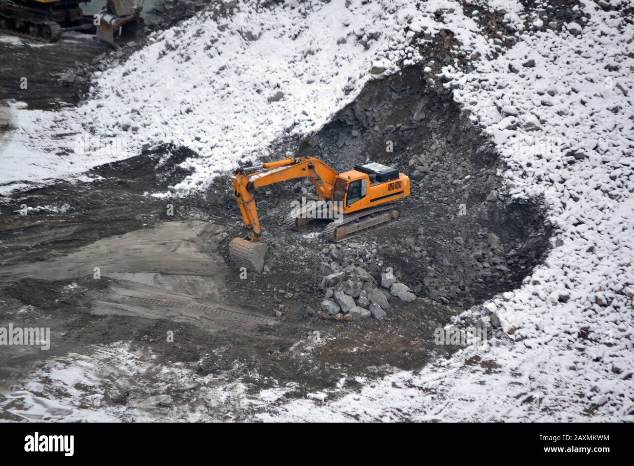 Machine for breaking stones in granite quarry in winter snowy day Stock Photo