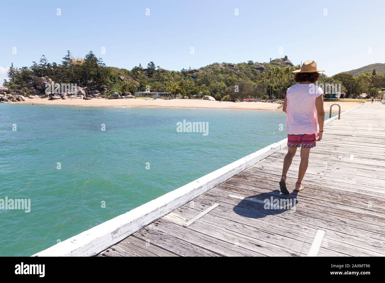 Curly hair man, with sun hat, walking on wooden dock of Magnetic Is. Stock Photo