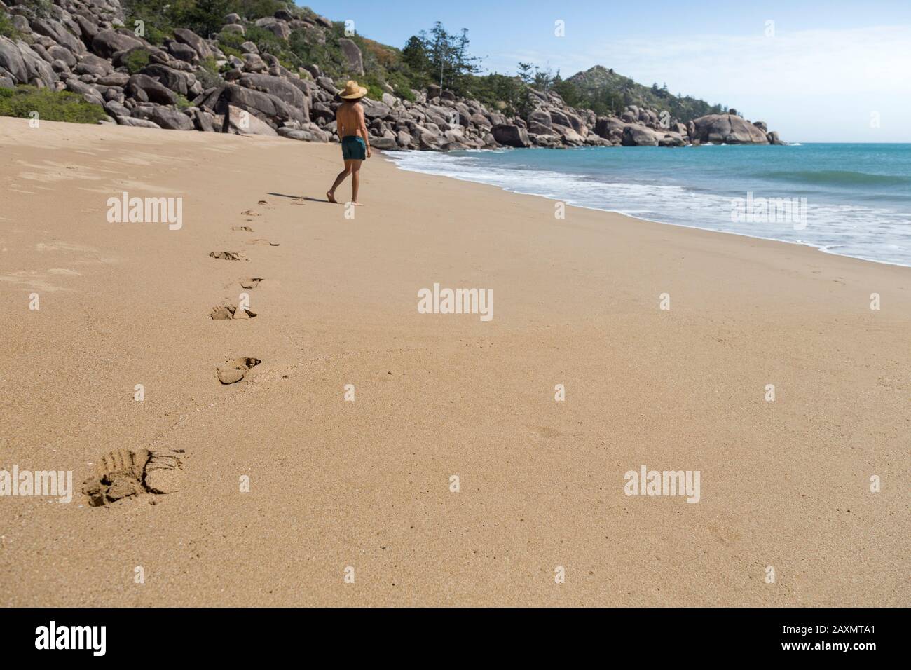 Footprints on sand left by male tourist wearing hat and green shorts Stock Photo