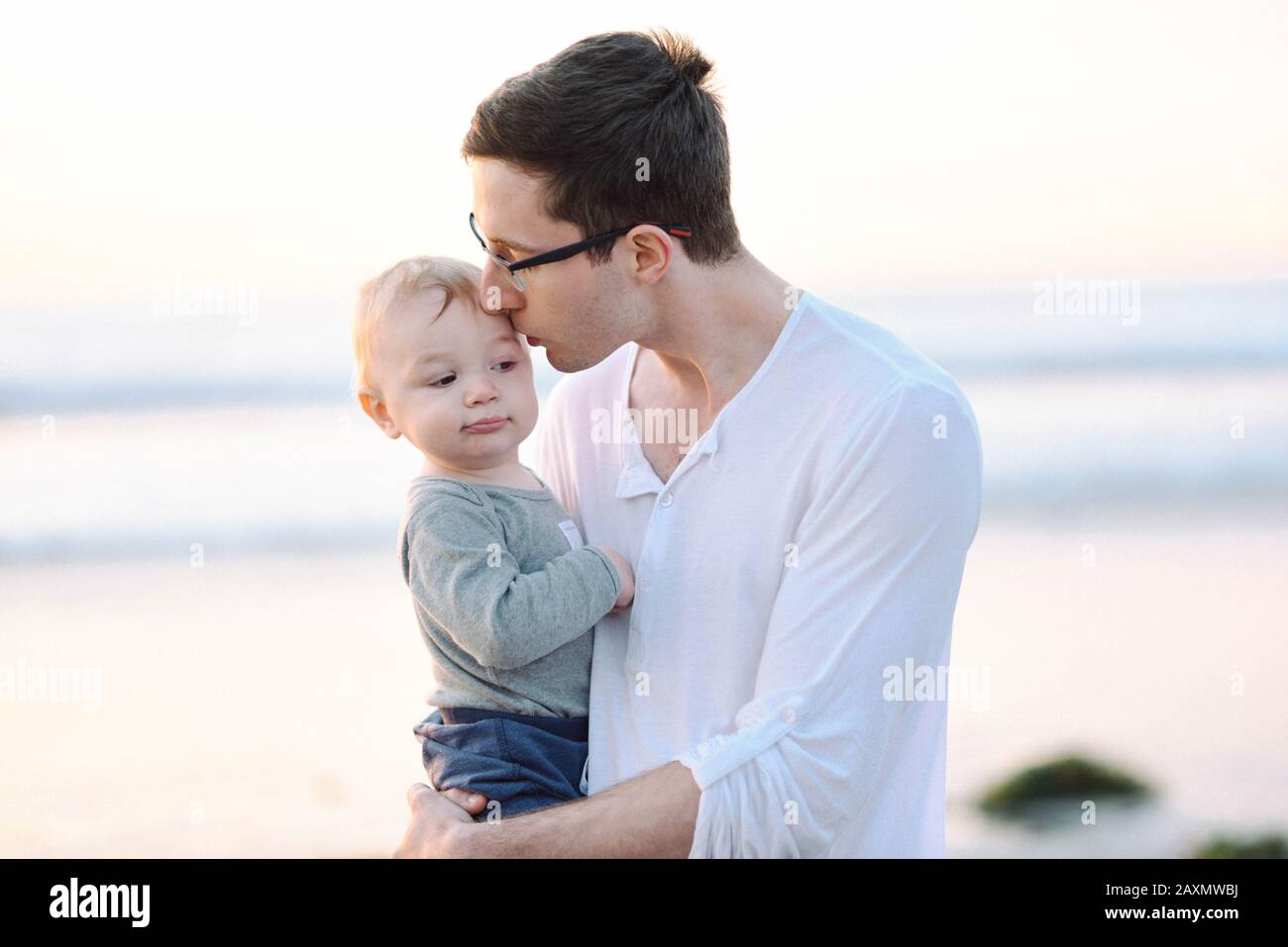 A young father giving his son a kiss on the temple at the beach Stock Photo  - Alamy