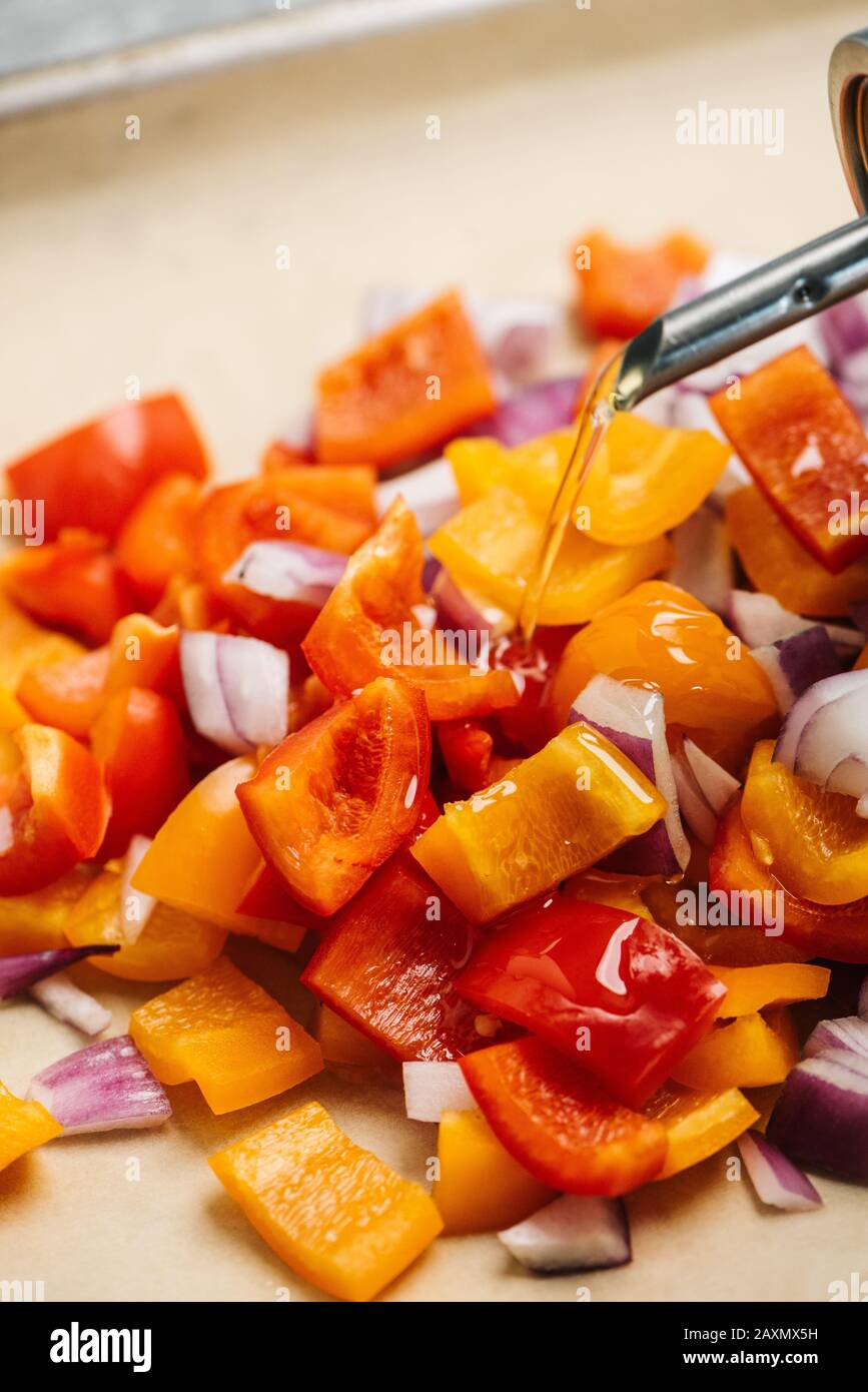 Pouring olive oil over veggies before roasting Stock Photo