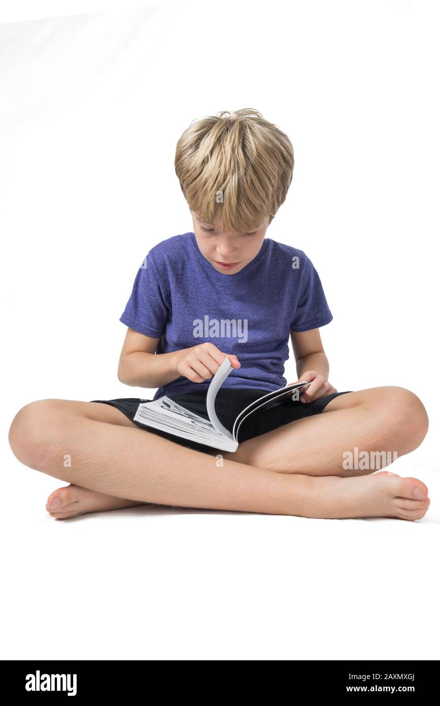 Portrait of a boy sitting and reading a book on white background Stock Photo