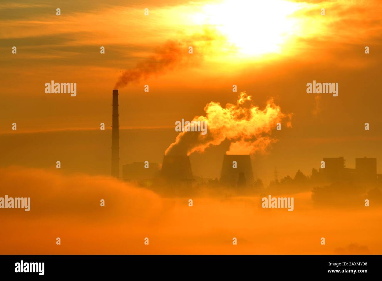 plant with pipes and smoke at sunset dawn. Red, orange cityscape. Landscape with smoke and morning fog. Contrasting the dark silhouette of the plant Stock Photo