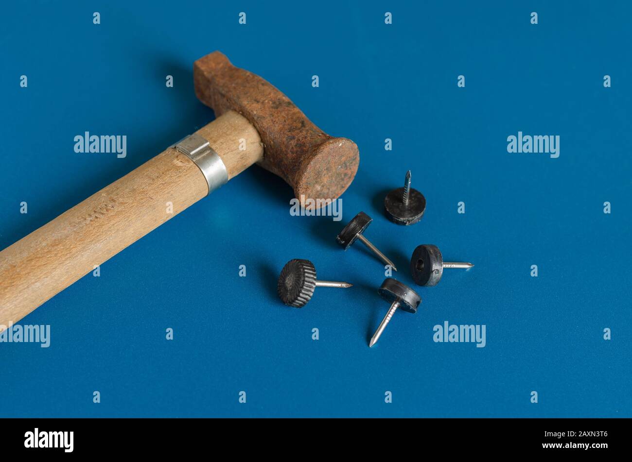 A small rusty hammer and five nails. Side view. Close-up. Selective focus. Stock Photo