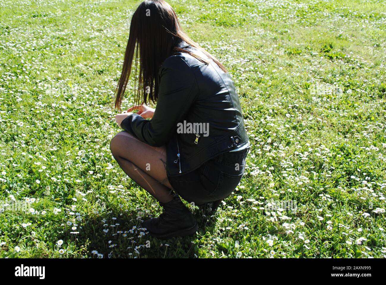A girl dressed in black picking up flowers Stock Photo
