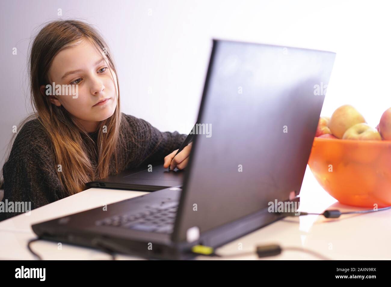 girl at home learns to draw on the laptop using a tablet and pen Stock Photo