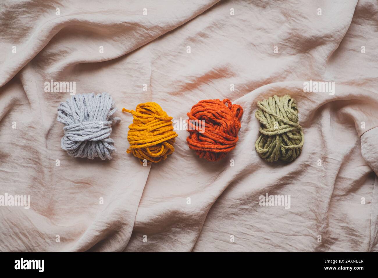 Macrame ropes in various colors, top view. Mustard, red, olive and white crochet threads in beautiful pastel backdrop, flat lay image Stock Photo