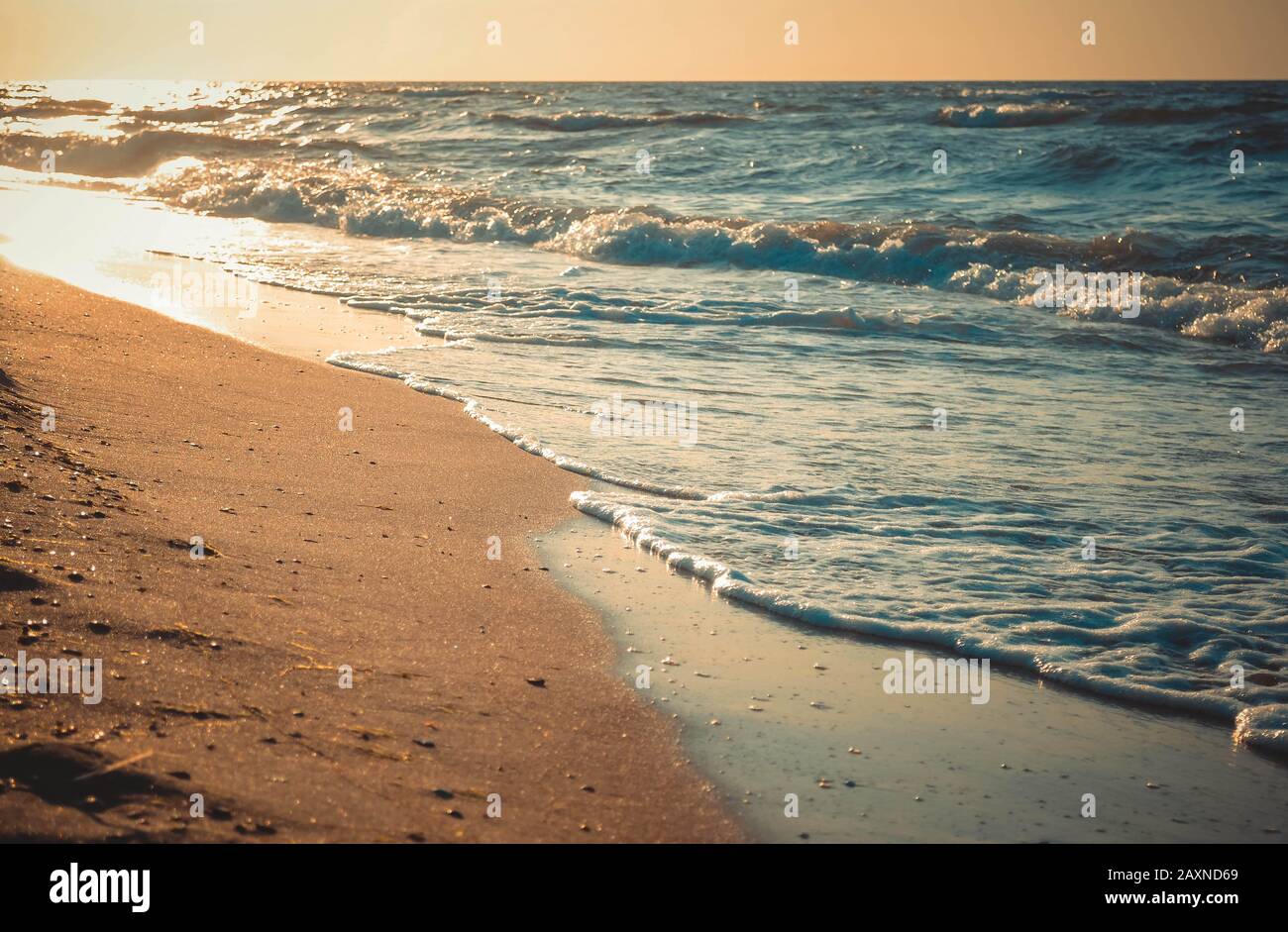 the sun is reflected in waves rolling on a sandy beach, close-up Stock Photo