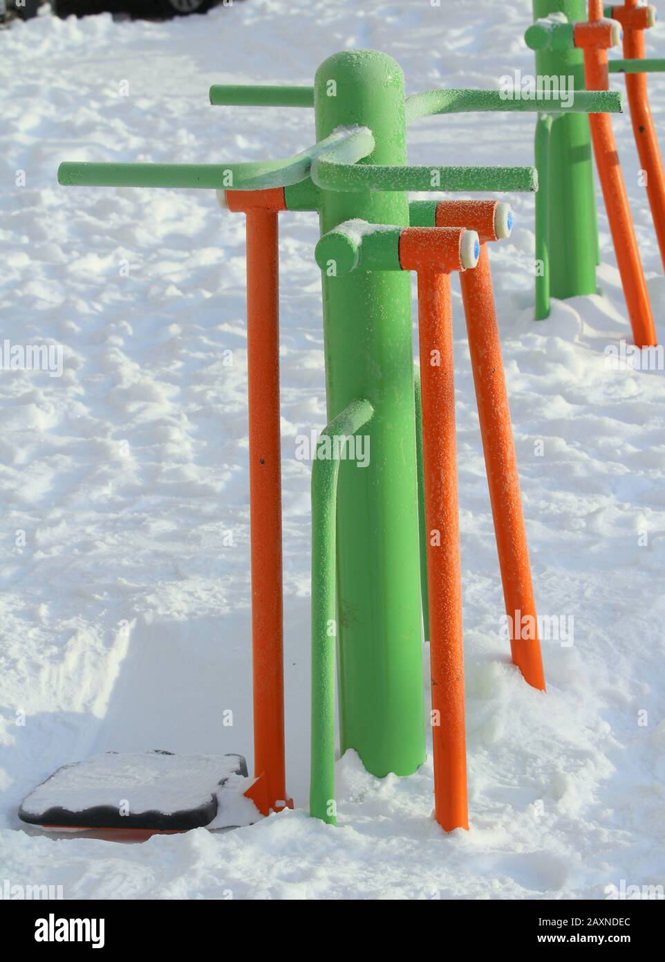 Outdoor fitness equipment on winter urban background, concept of active winter recreation, health care. Vibrant cheerful greens and oranges color. Stock photo with empty space for text. Stock Photo