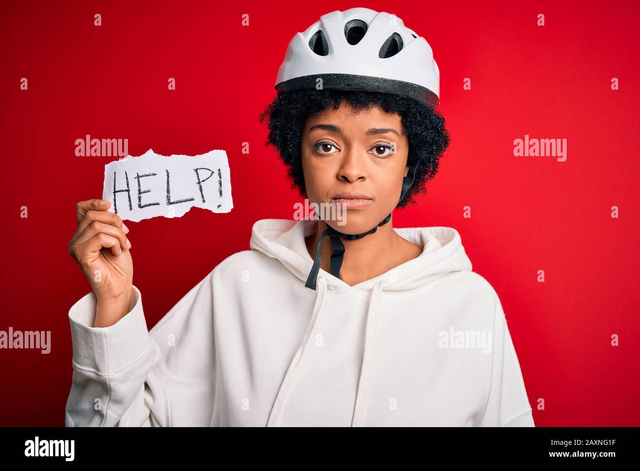 African American woman with curly hair wearing bike helmet holding paper  with help message with a confident expression on smart face thinking  serious Stock Photo - Alamy