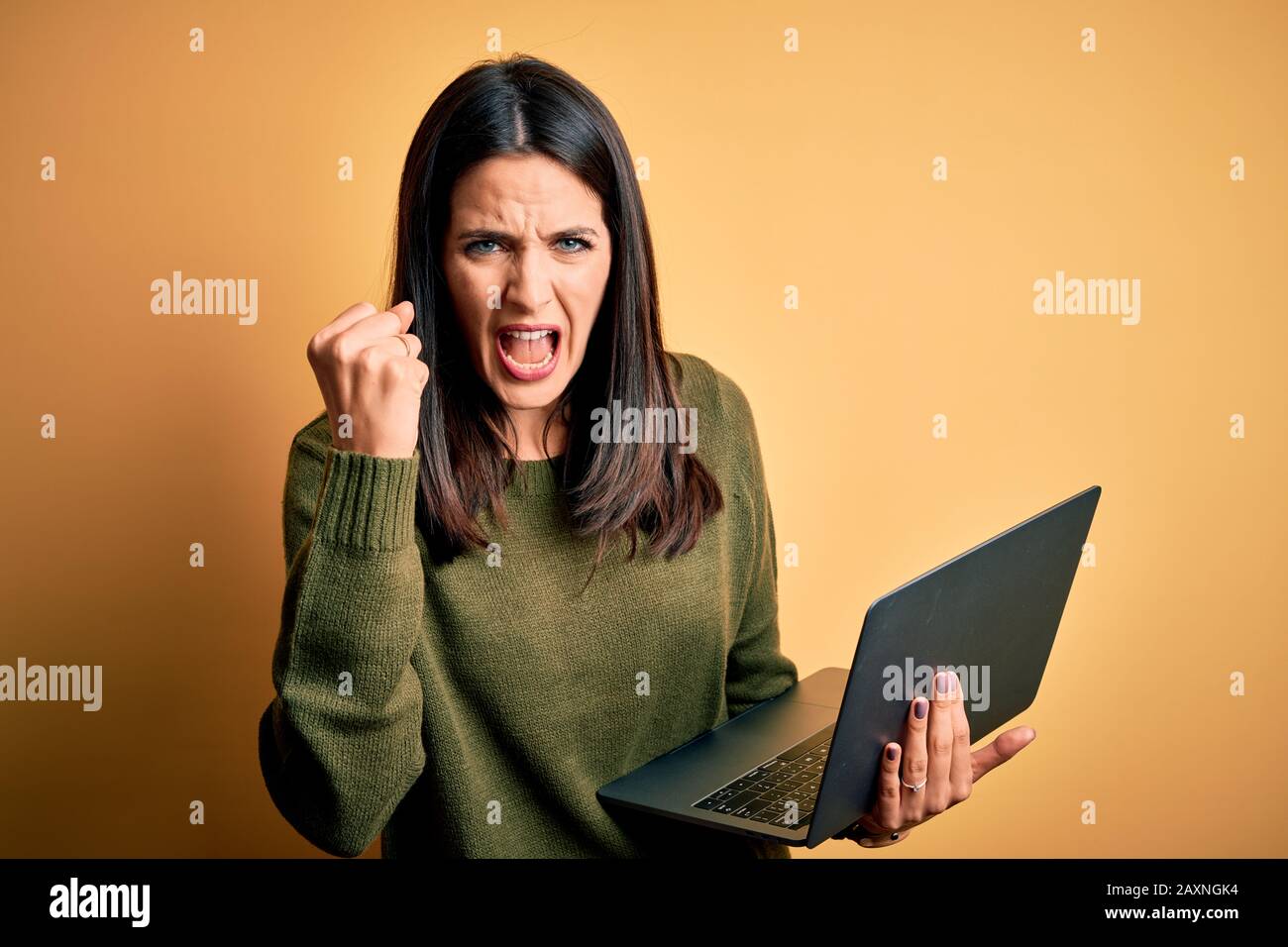 Young brunette woman with blue eyes working using computer laptop over ...