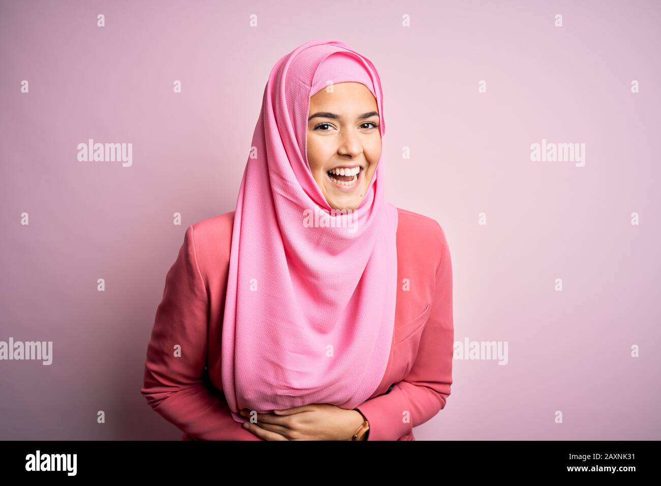 Young beautiful girl wearing muslim hijab standing over isolated pink  background smiling and laughing hard out loud because funny crazy joke with  hand Stock Photo - Alamy