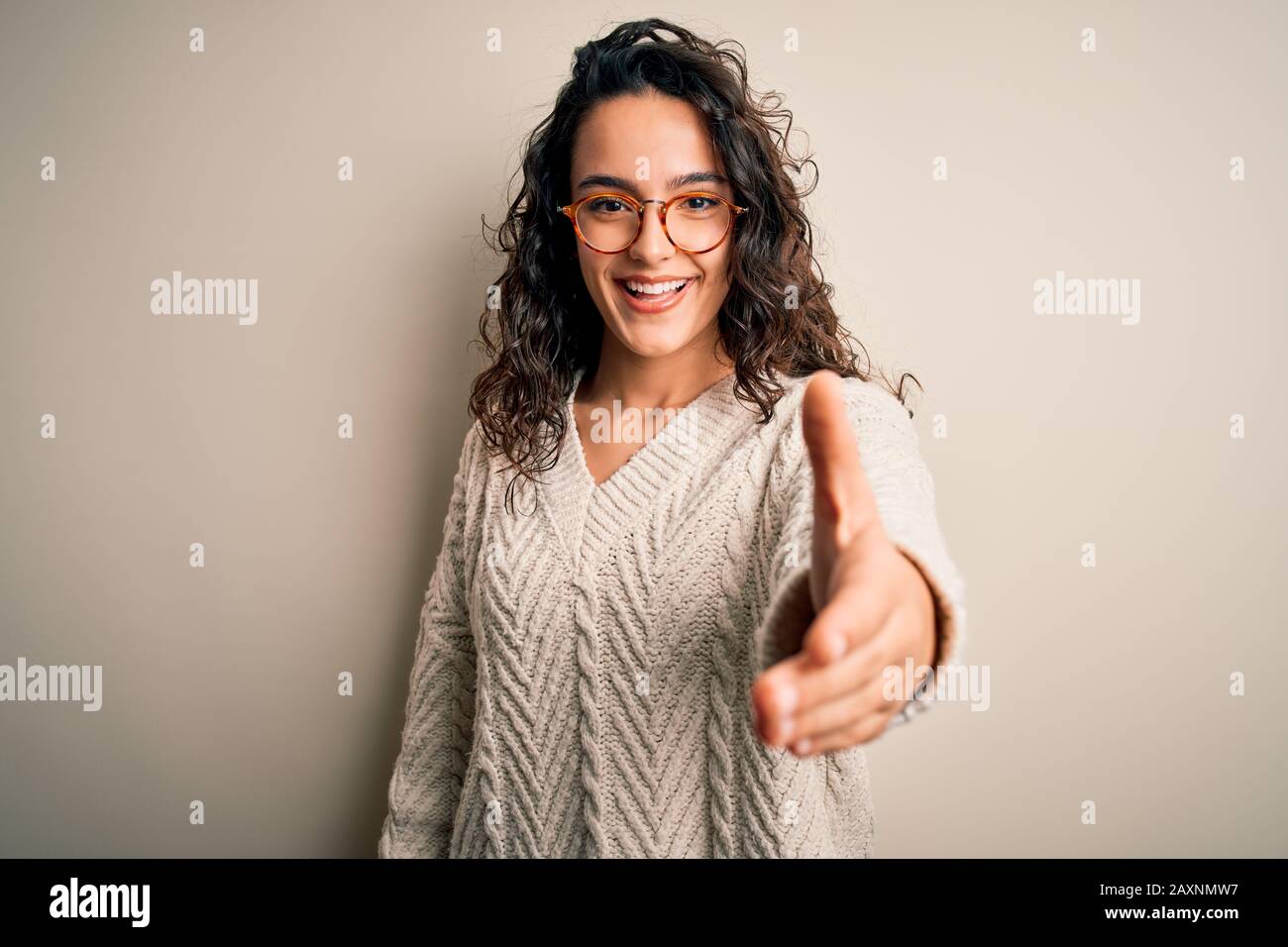 Beautiful woman with curly hair wearing casual sweater and glasses over ...