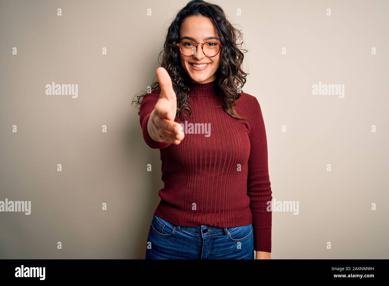 Beautiful woman with curly hair wearing casual sweater and glasses over ...