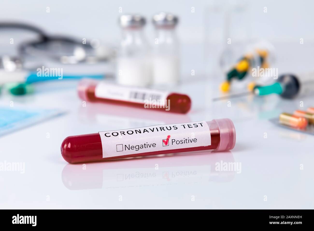 Blood test tube with the Coronavirus disease for virus test and research. Blood test tube with protective masks, medicines, thermometer, stethoscope a Stock Photo