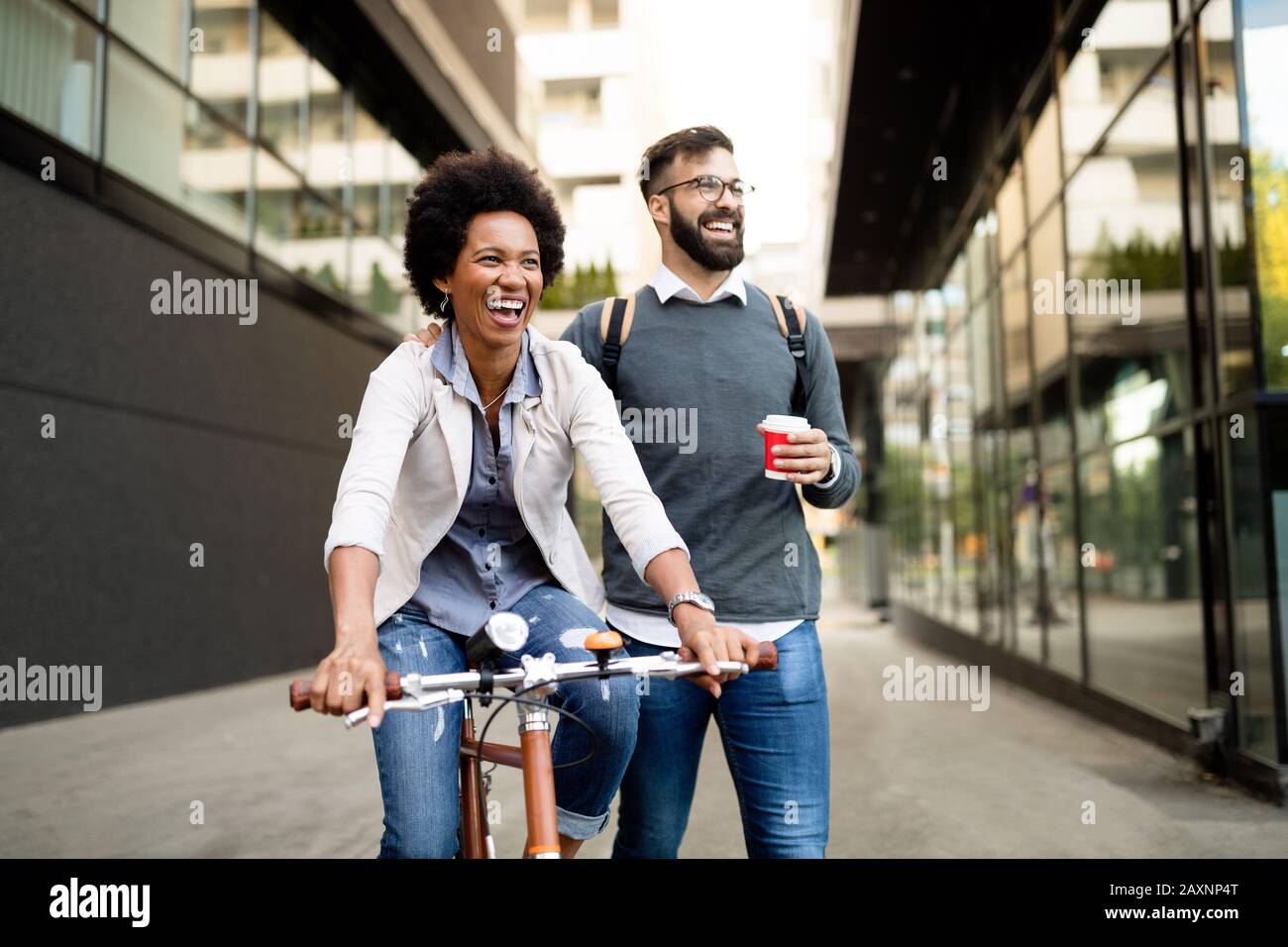 Happy business couple riding bike through city and having fun Stock Photo