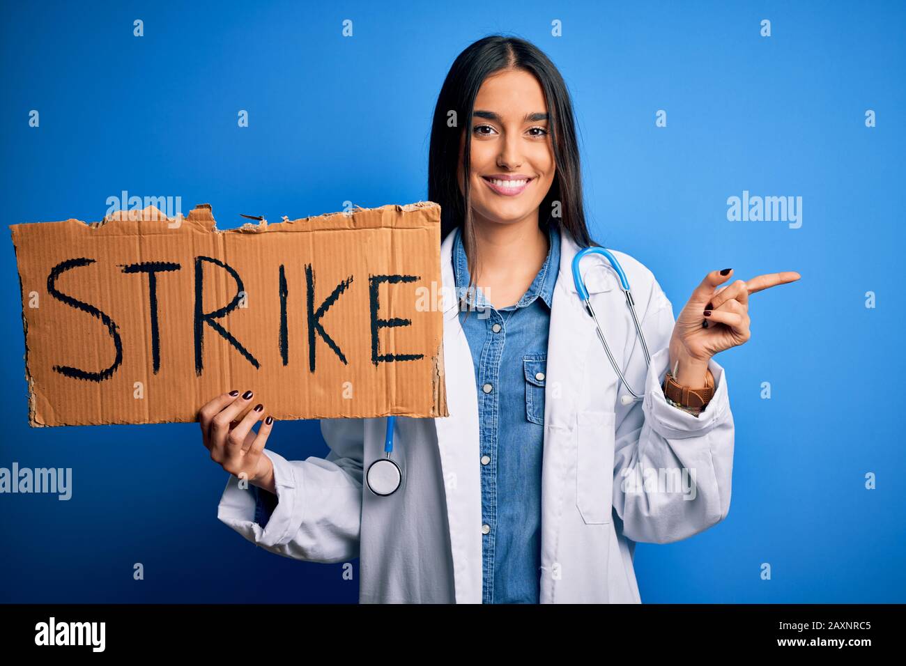 Young doctor woman wearing stethoscope holding cardboard banner ...