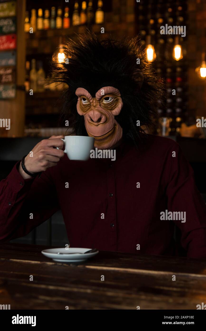 Man with monkey mask in the cafe, half portrait Stock Photo