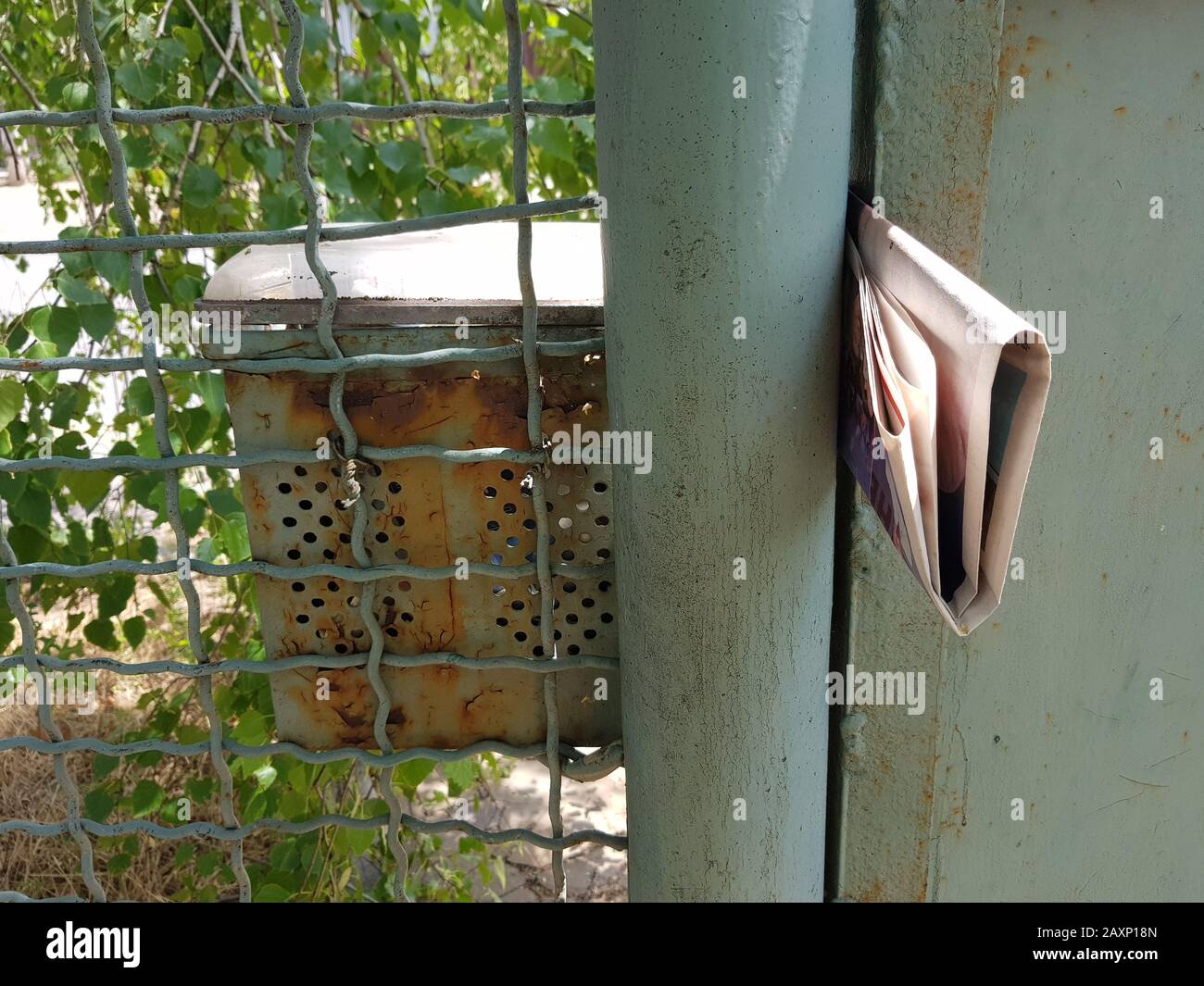 Letters in an old mailbox and a newspaper sticking out at the gate. Stock Photo