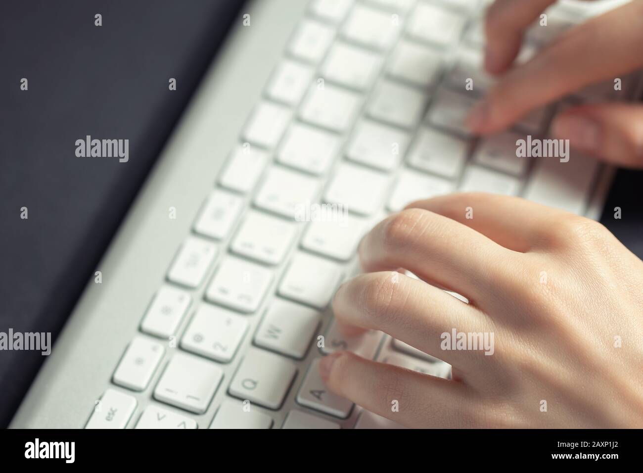 Girl works at home at the computer. Female hands are typing on the keyboard, close up. Stock Photo