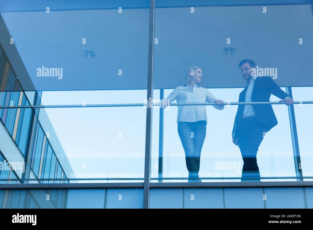 Young businessman and young businesswoman in modern office building behind glass front Stock Photo