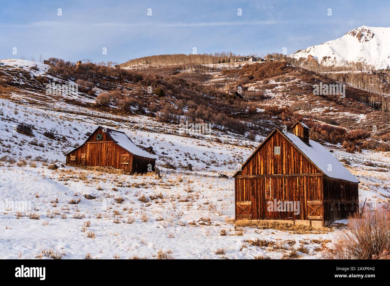 A pair of rustic, wood barns catch evening sunlight in the foothills of the San Juan Mountains in Telluride, Colorado, USA. Stock Photo