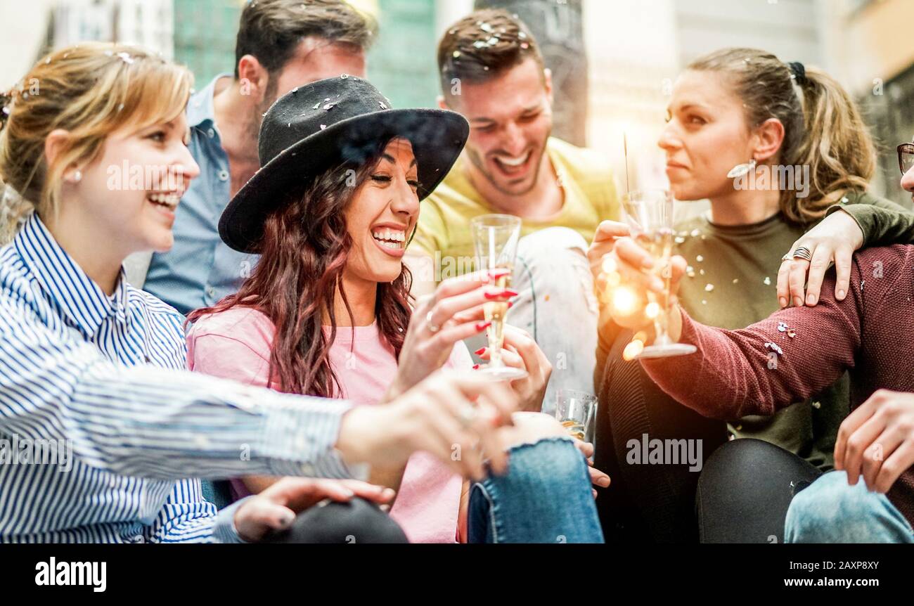 Group of happy friends having party with champagne,confetti and sparklers outdoor - Young students celebrating drinking and laughing - Friendshi and y Stock Photo