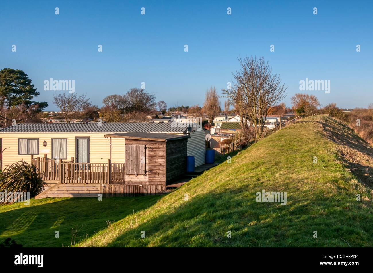 Caravans and holiday homes on the seaward side of the sea wall flood defence at Snettisham on the east coast of The Wash, Norfolk. Stock Photo