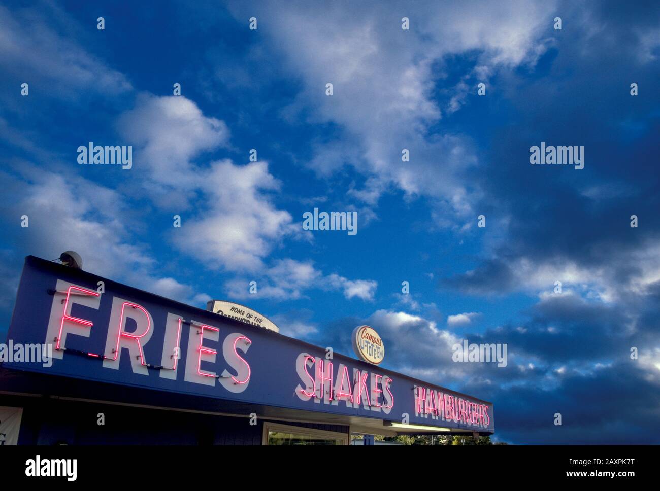 Neon sign on a diner advertising fries shakes and hamburgers under a darkening evening sky Stock Photo
