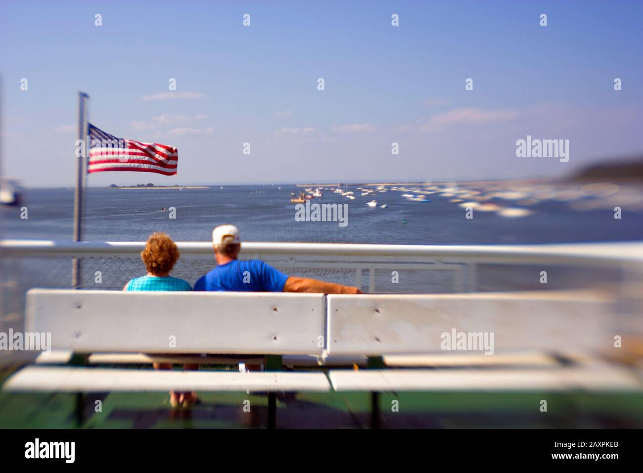 A senior couple relaxing on a bench on board a ferry in Long Island sound, Connecticut USA Stock Photo