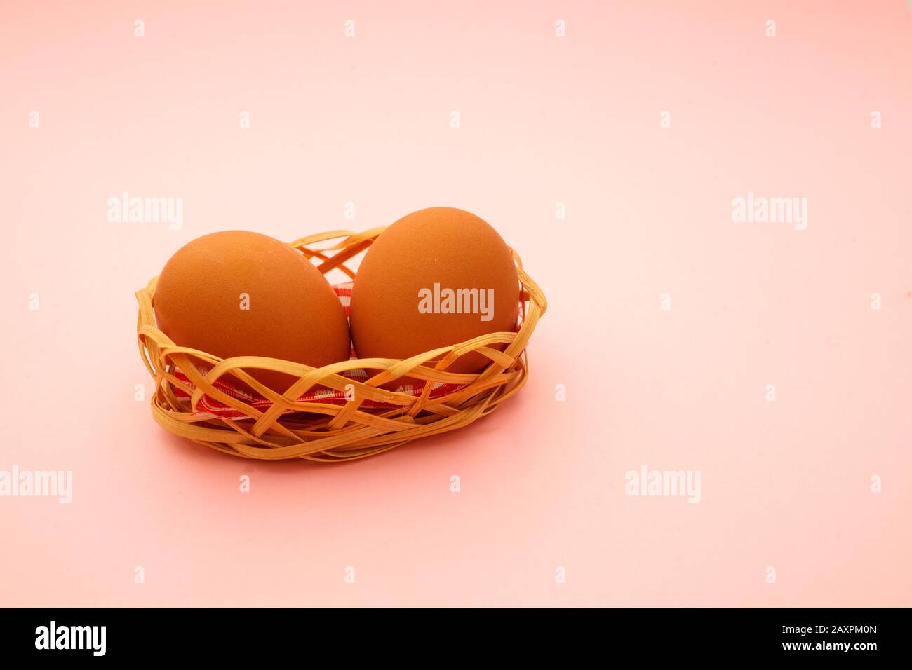 Wicker basket with Easter eggs on pink background Stock Photo