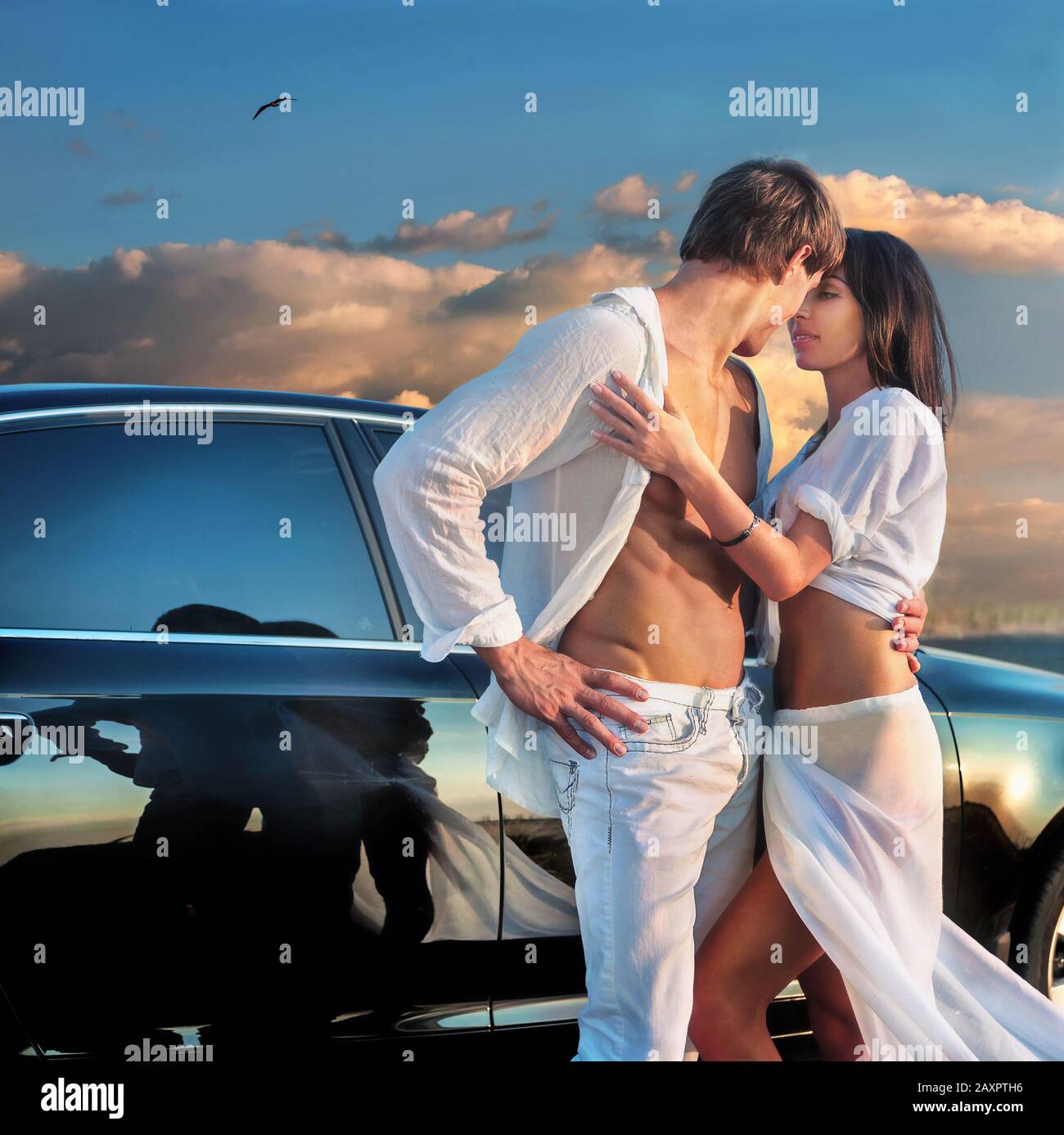 Fashion portrait of romantic young couple in love near car at sunset Stock Photo