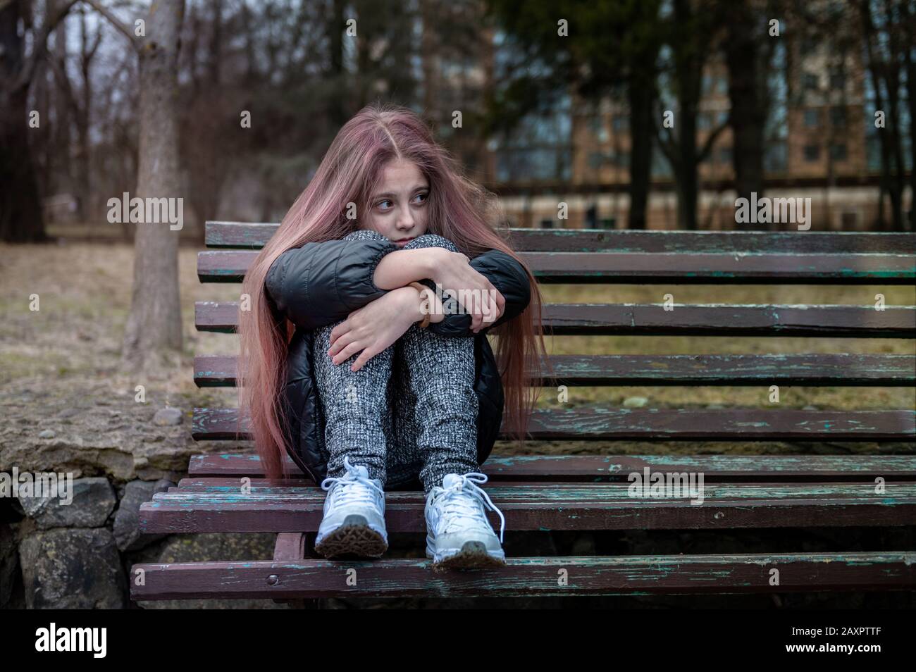 Sad depressed young girl sitting on a bench in a park Stock Photo Alamy