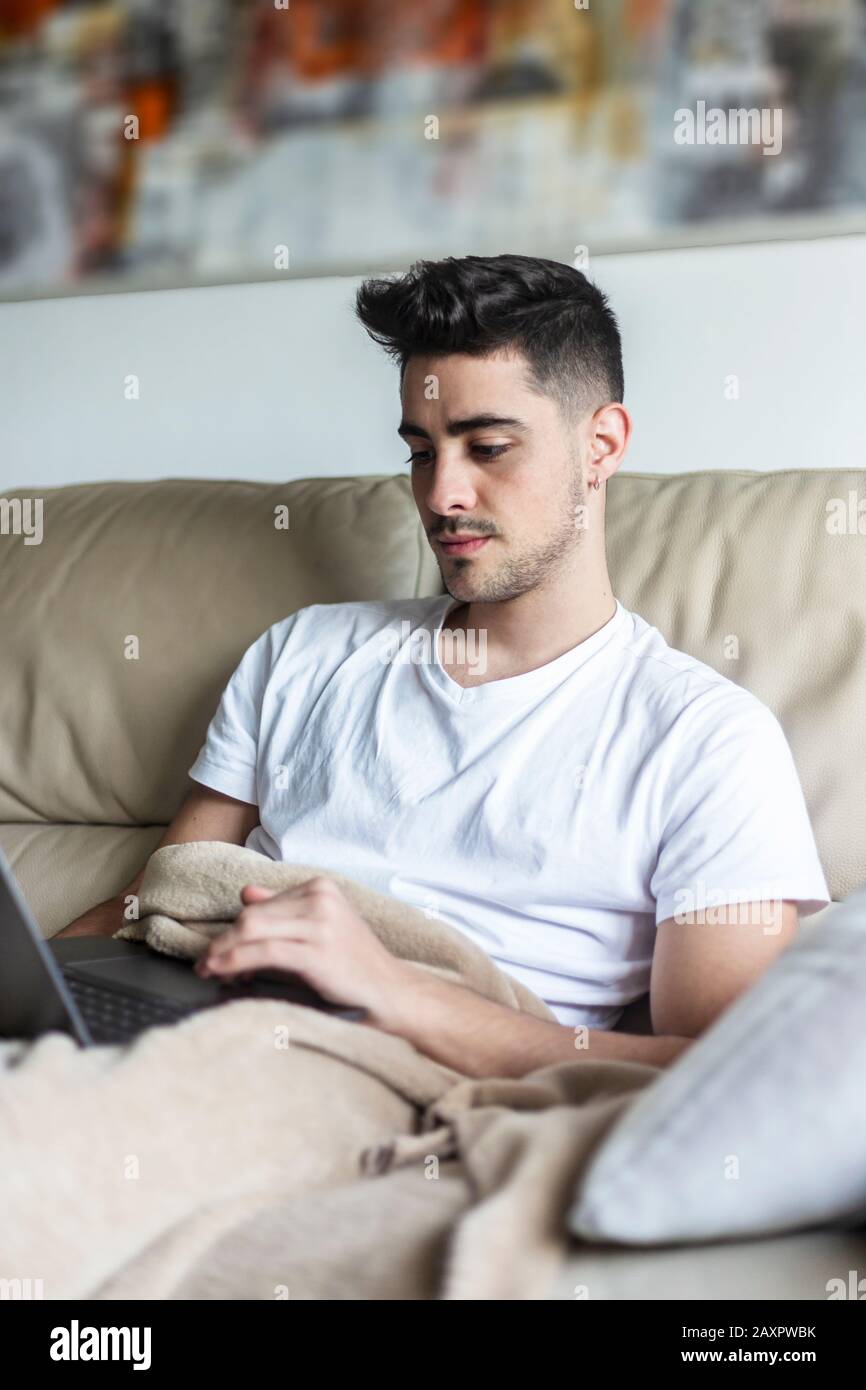 Young male man relaxing on sofa while using laptop Stock Photo