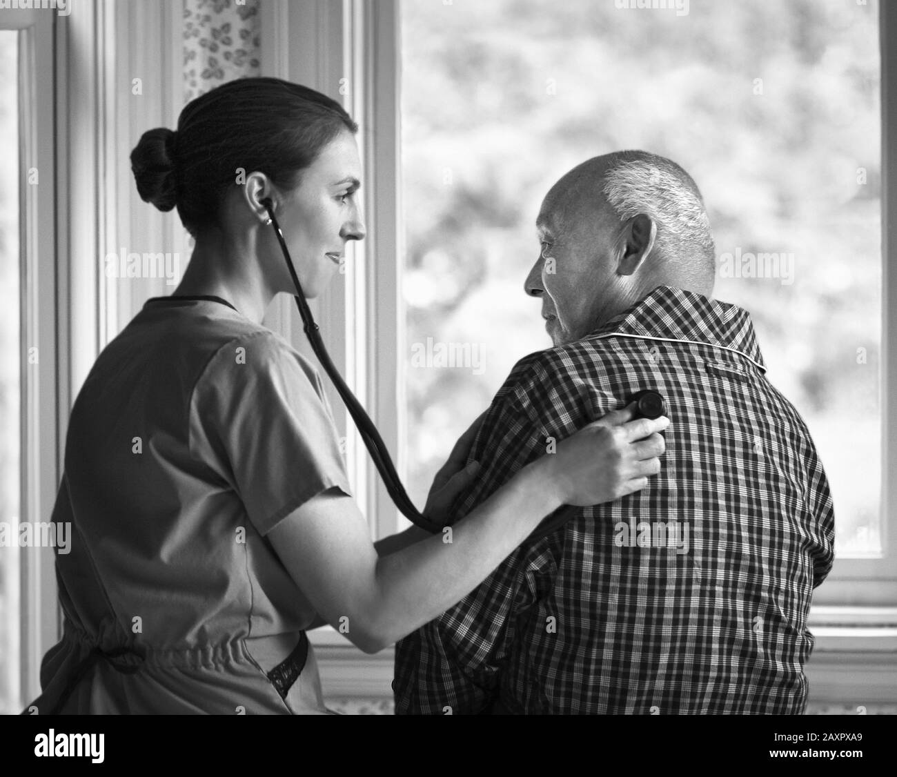 Female nurse checking an elderly man's heartbeat with a stethoscope. Stock Photo