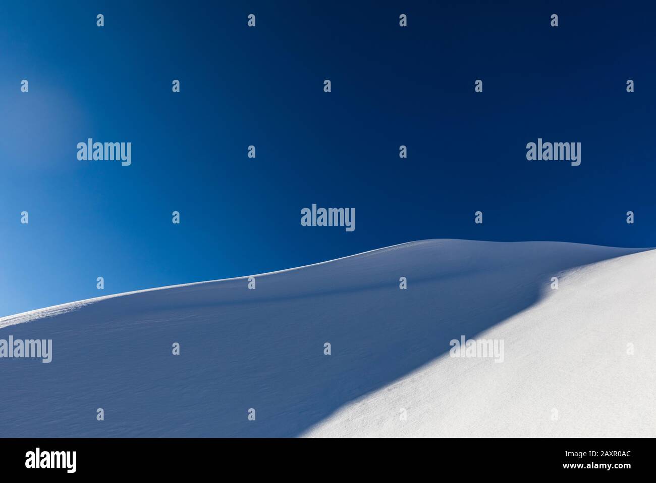 minimalist landscape with bright snow covered mountain and blue sky Stock Photo