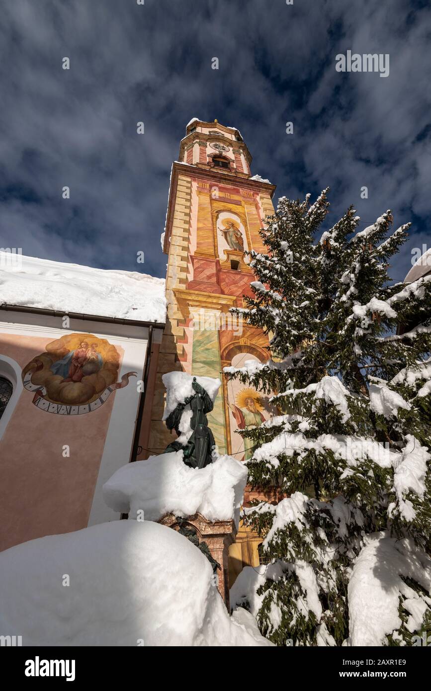 The monument of M. Klotz with snow and church tower in Mittenwald Stock Photo
