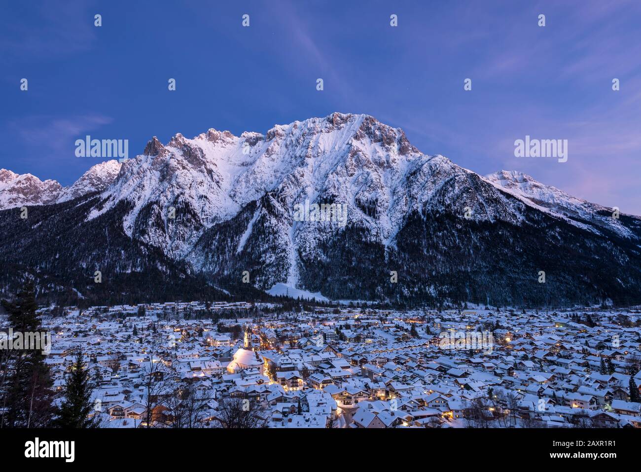 The Mittenwald market in winter during nightfall with lots of snow and the Karwendel in the background. Stock Photo
