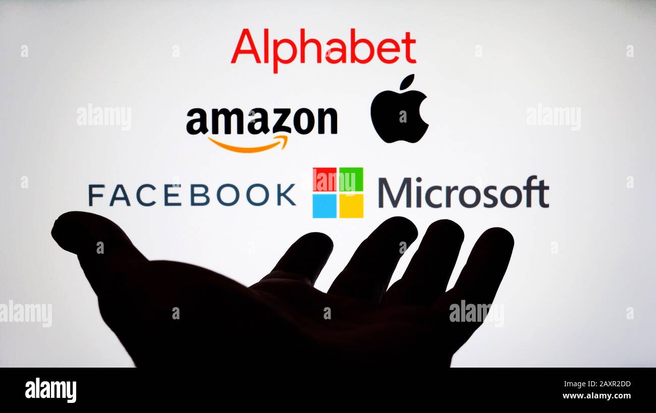 Big Tech company logos: Alphabet, Amazon, Apple, Facebook and Microsoft on a blurred screen and a silhouette of the hand. Not a montage Stock Photo