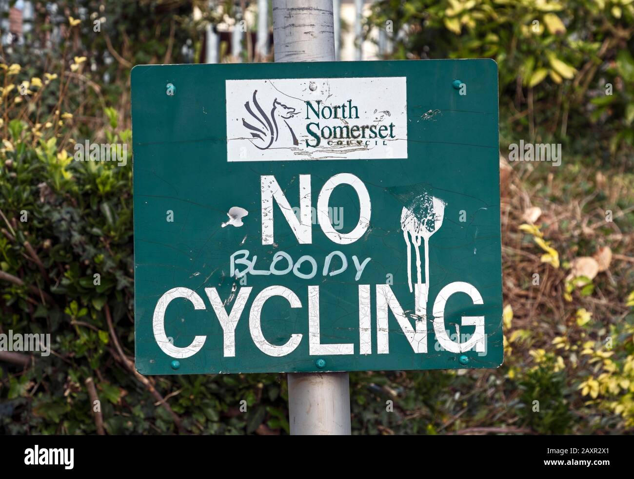 A battered, sign forbidding cycling in Ashcombe Park, Weston-super-Mare, UK which has been altered to read “NO BLOODY CYCLING” Stock Photo