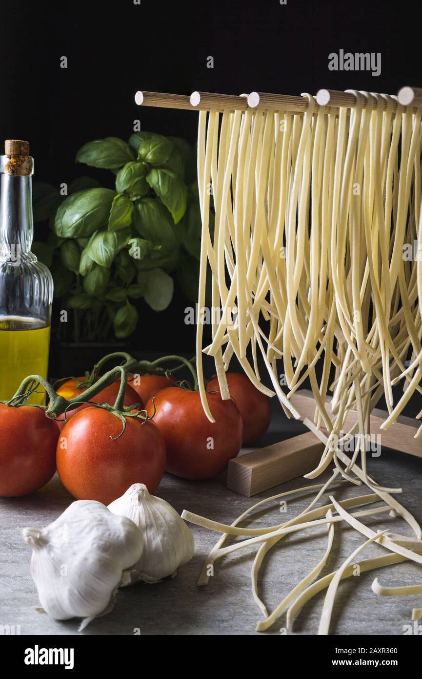 https://c8.alamy.com/comp/2AXR360/fresh-pasta-noodles-drying-on-a-wooden-rack-2AXR360.jpg