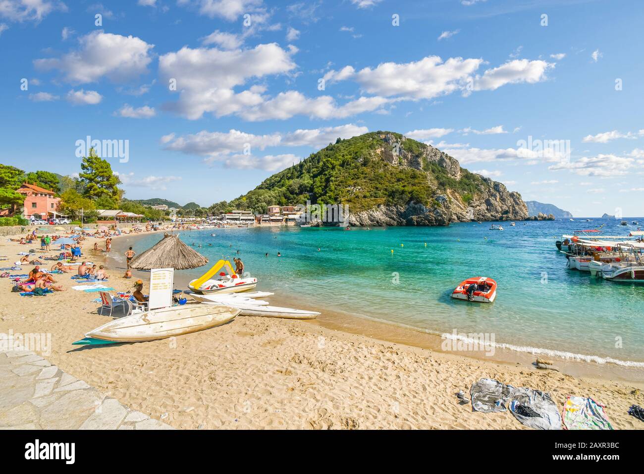 A sunny day at Palaiokastritsa beach as tourists sunbathe and swim in the sea on the island of Corfu, Greece. Stock Photo